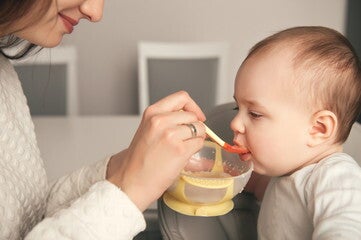 Mamá dando cereal NESTUM para bebés a su hija