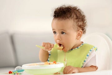 Bebé comiendo solo fruta en puré Bebé comiendo solo fruta en puré
