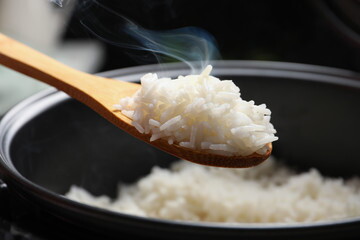 Cuchara de madera sacando arroz de una olla Cuchara de madera sacando arroz de una olla