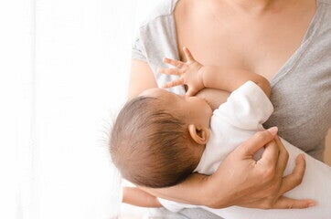 Una madre dando leche materna a su bebé Una madre dando leche materna a su bebé