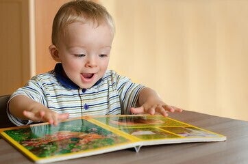 Un niño sonriendo mientra mira un libro de cuentos Un niño sonriendo mientra mira un libro de cuentos