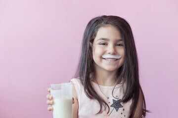 Una niña sonriendo con un vaso de leche en la mano Una niña sonriendo con un vaso de leche en la mano