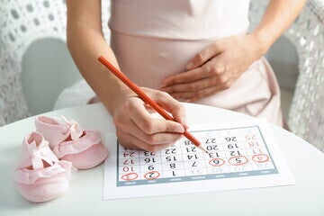 Una mujer embarazada revisando el calendario Una mujer embarazada revisando el calendario