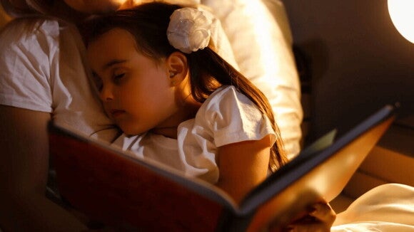 Habitos saludables de sueño Niña se queda dormida mientras su mamá le leía un cuento y fomentaba hábitos saludables para niños