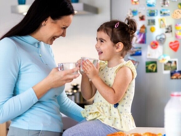 Familia con una niña compartiendo una comida en casa, sentados en la cocina y disfrutando juntos.