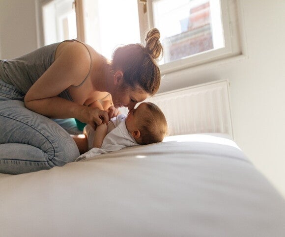 Las mamás pueden ayudar en el desarrollo motriz de los bebés por medio de juegos y actividades Bebé acostado y mamá jugando con él