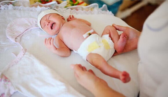 Bebé recién nacido sobre una cama de maternidad Bebé recién nacido sobre una cama de maternidad