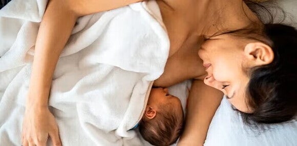 La leche materna pasa por muchos procesos, desde el calostro hasta la leche madura Mamá acostada alimentando a su bebé recién nacido.