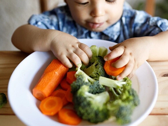 Nutrientes que fortalecen las defensas niño comiendo plato de verduras