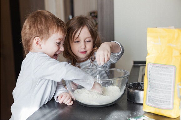 Snacks para el Día del Niño niño y niña cocinando juntos en un bol lleno de harina