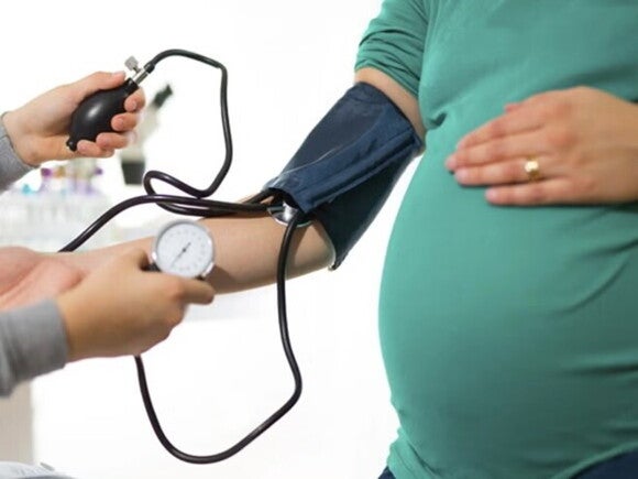 Hipertensión gestacional Doctor y mujer embarazada con un tensiómetro en el brazo midiendo su presión alta en el embarazo