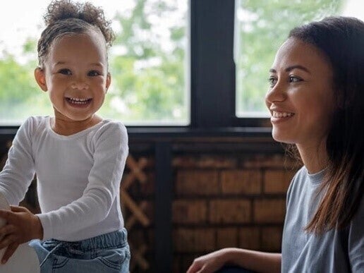 Madre y niña pequeña jugando y riendo.