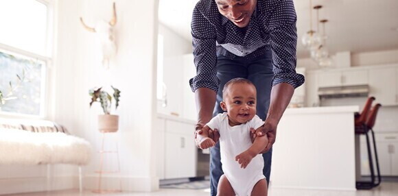 El entorno paternal del bebé de 8 meses Padre sosteniendo a su bebé en el suelo