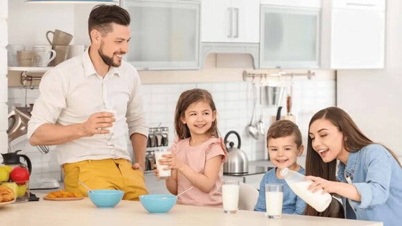 Niño sonriendo mientras su familia desayuna Niño sonriendo mientras su familia desayuna