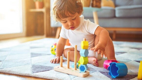 Los juguetes para niños adecuados a su edad Un niño jugando encima de una alfombra