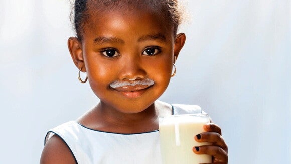 Niña tomando un vaso con leche, ideal para su crecimiento y desarrollo