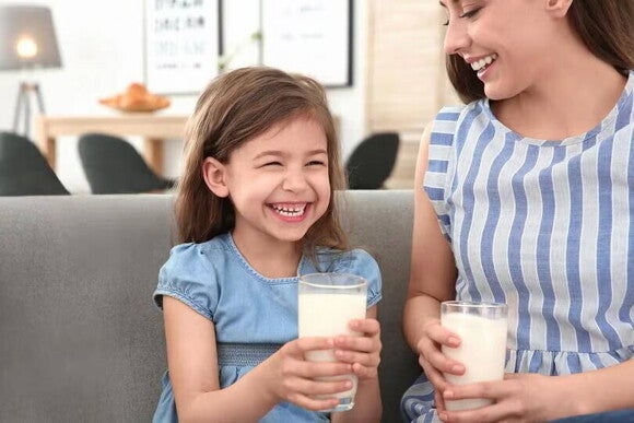 Mamá e hija alegre tomando un vaso con leche KLIM®. Mamá e hija alegre tomando un vaso con leche KLIM®.