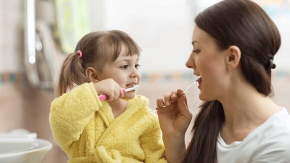 mama e hija cepillandose los dientes