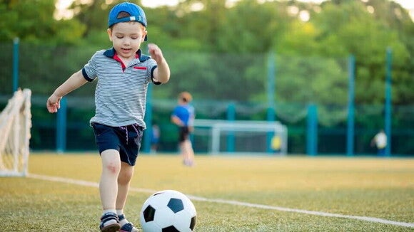 niño jugando futbol en una cancha