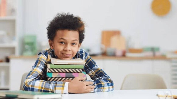 niño sosteniendo su cabeza sobre varios libros niño sosteniendo su cabeza sobre varios libros