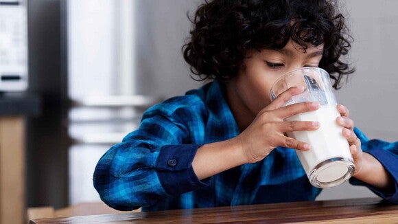 Niño tomando un vaso de leche deslactosada en un vaso de vidrio