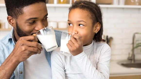 Papá e hija alegre disfrutando de los beneficios de un vaso de leche KLIM®. Papá e hija alegre disfrutando de los beneficios de un vaso de leche KLIM®.