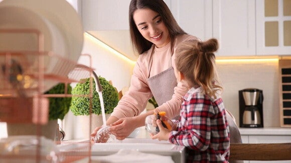 una joven madre lavando la loza con su hija