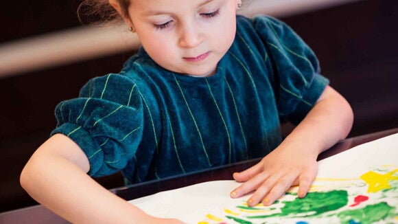 Una niña haciendo una actividad de arte pintando con sus dedos Una niña haciendo una actividad de arte pintando con sus dedos