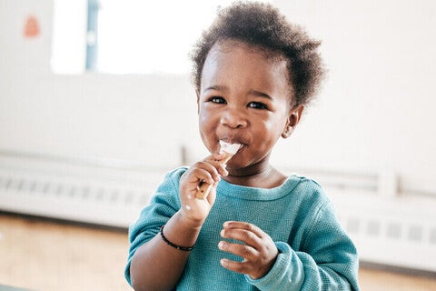 Niño pequeño sonriendo y comiendo con una cuchara